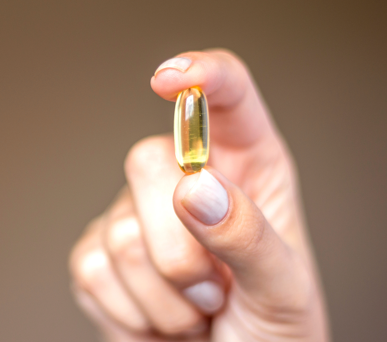 Hand holding omega softgel capsule